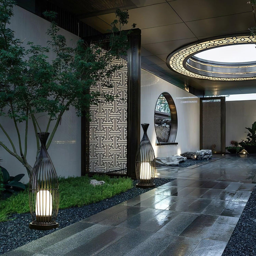 The lantern lit in a courtyard beside a small tree and a screen