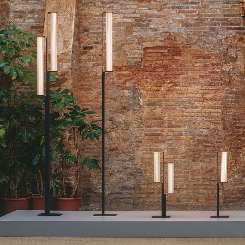 Two heights lit together against a brick wall with potted planting
