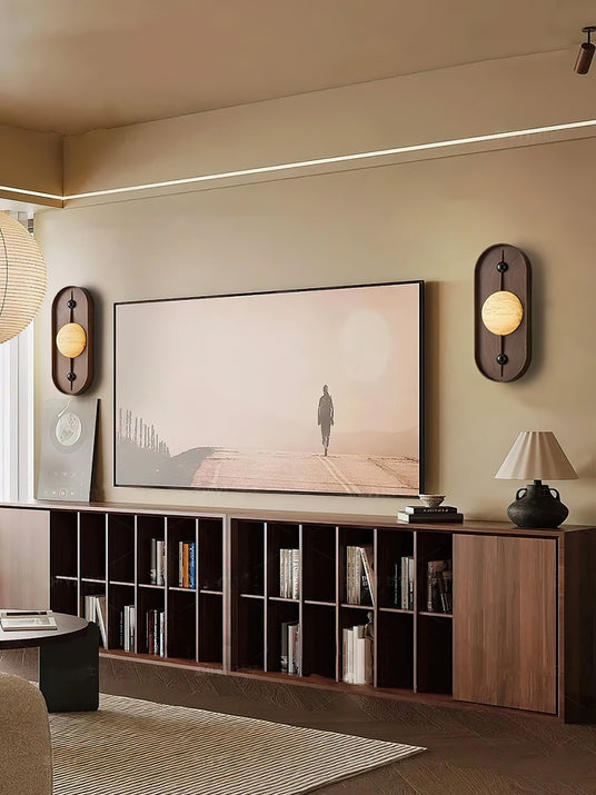 Two sconces lit either side of framed artwork above a long media cabinet