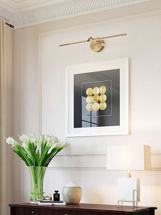 Lit above framed art on a console with tulips, a table lamp and a dark cabinet