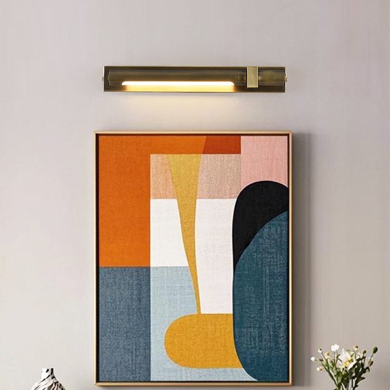 Bronze bar lit over a framed abstract canvas with flowers on the shelf below