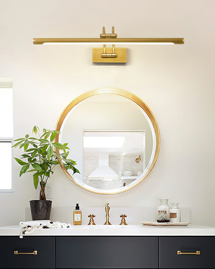 Long brass bar lit over a round mirror above a navy vanity with bottles and a plant