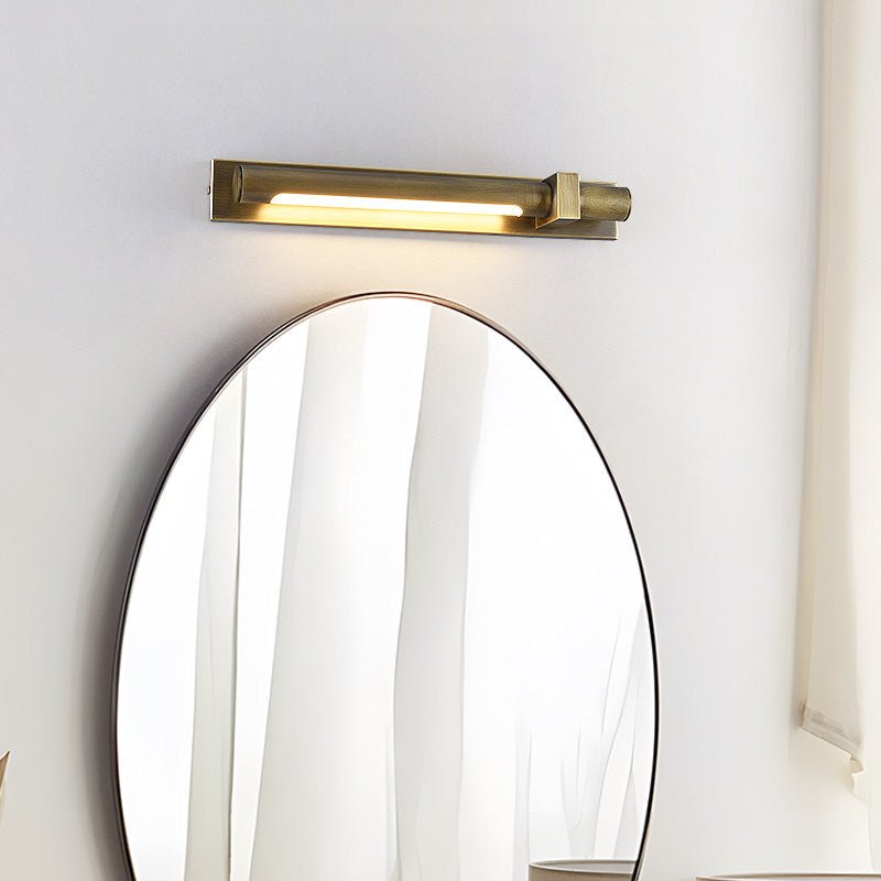 Bronze bar lit above a tall oval mirror beside a pale curtain