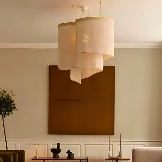 Overlapping fabric shades hung in a warm living room with a wood panel