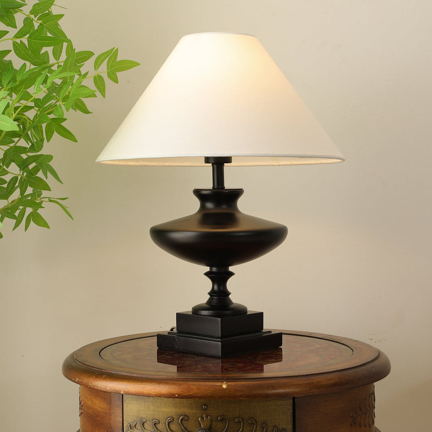 Close view of the lit white empire shade above the black urn base