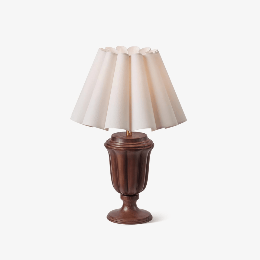 Large table lamp with a pleated scalloped shade on a carved urn base
