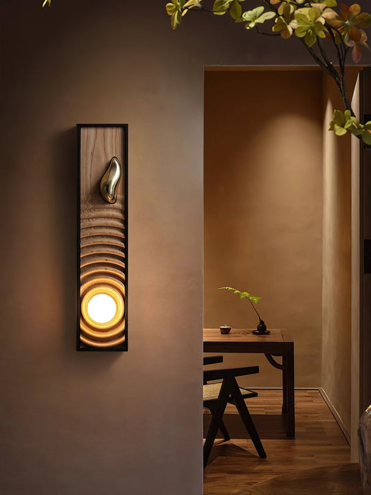 Sconce lit beside an open doorway with a wood desk and chair in the room beyond