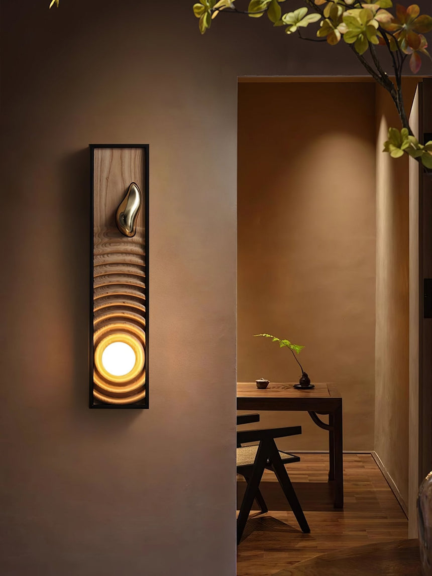 Sconce lit beside an open doorway with a wood desk and chair in the room beyond