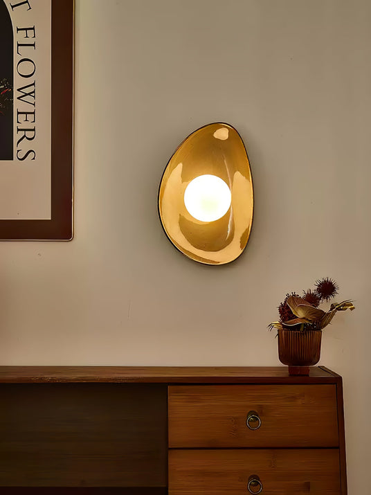 The pebble light lit gold above a wood dresser beside a framed print and dried flowers