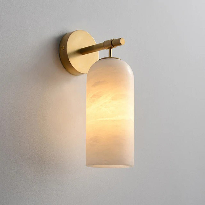 Pillar wall sconce with a lit stone cylinder hanging from a gold disc and arm