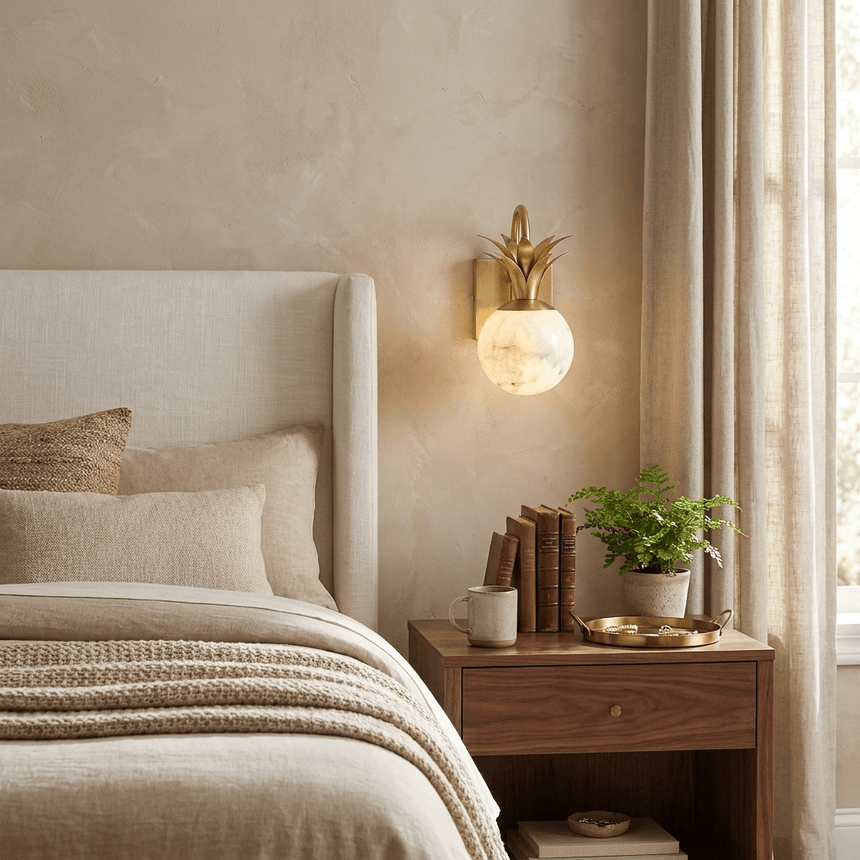 The sconce lit beside a bed with a knit throw and a wood nightstand