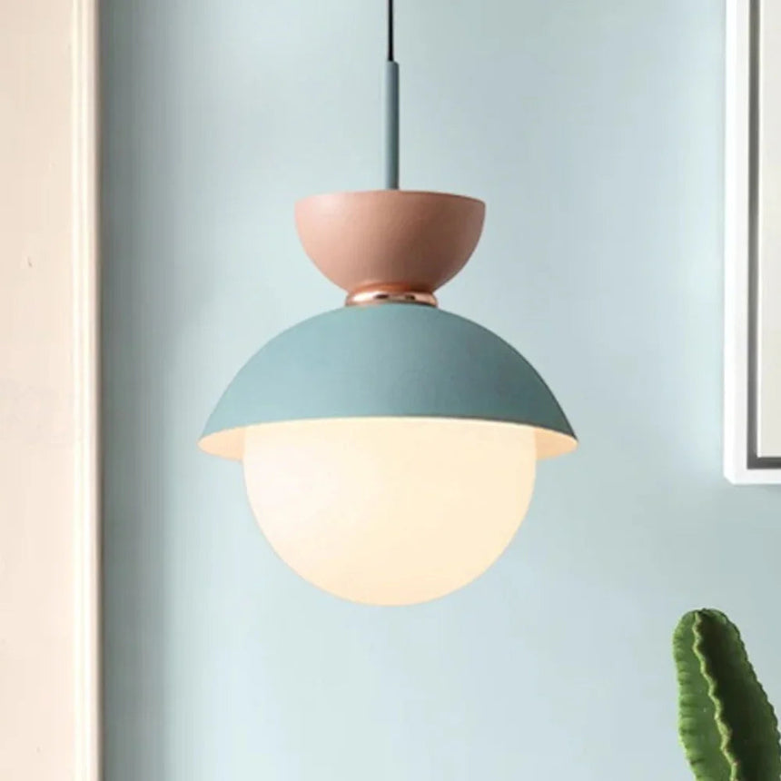 Three capped opal globes in pink and blue lit in a row on a pale wall