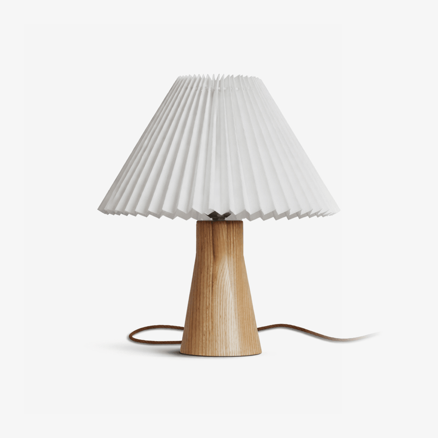 Pleated table lamp with a white shade on a pale wood base, plain ground