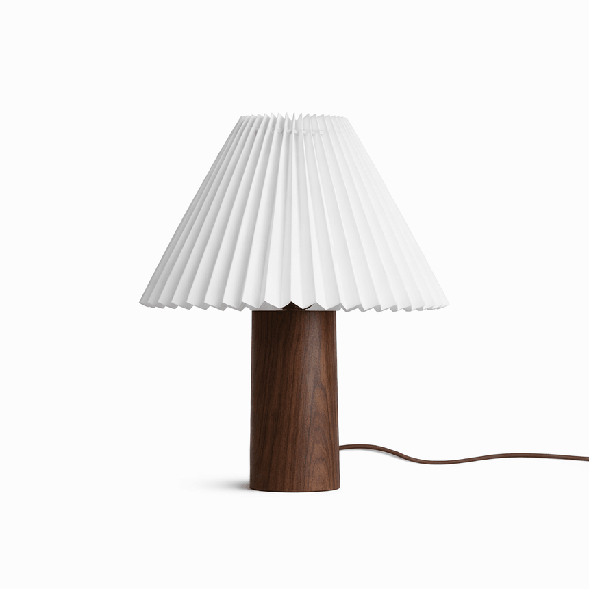Pleated white shade on a walnut base seen front on against a white ground