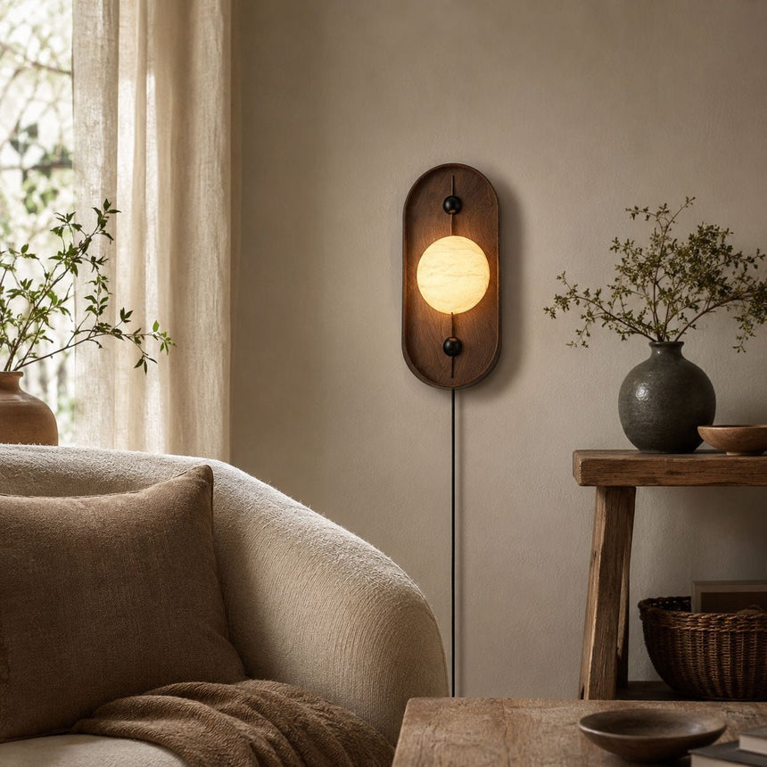 Lamp lit above a console beside a pale armchair and a drawn curtain