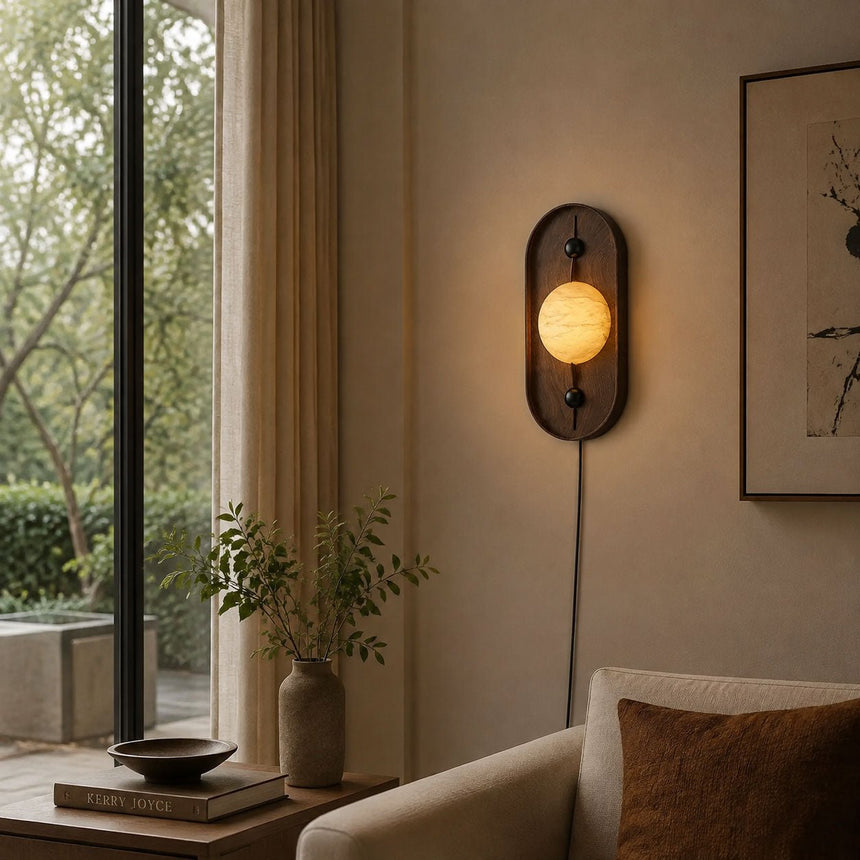 Lamp lit beside a tall window above a stack of books and a curtain