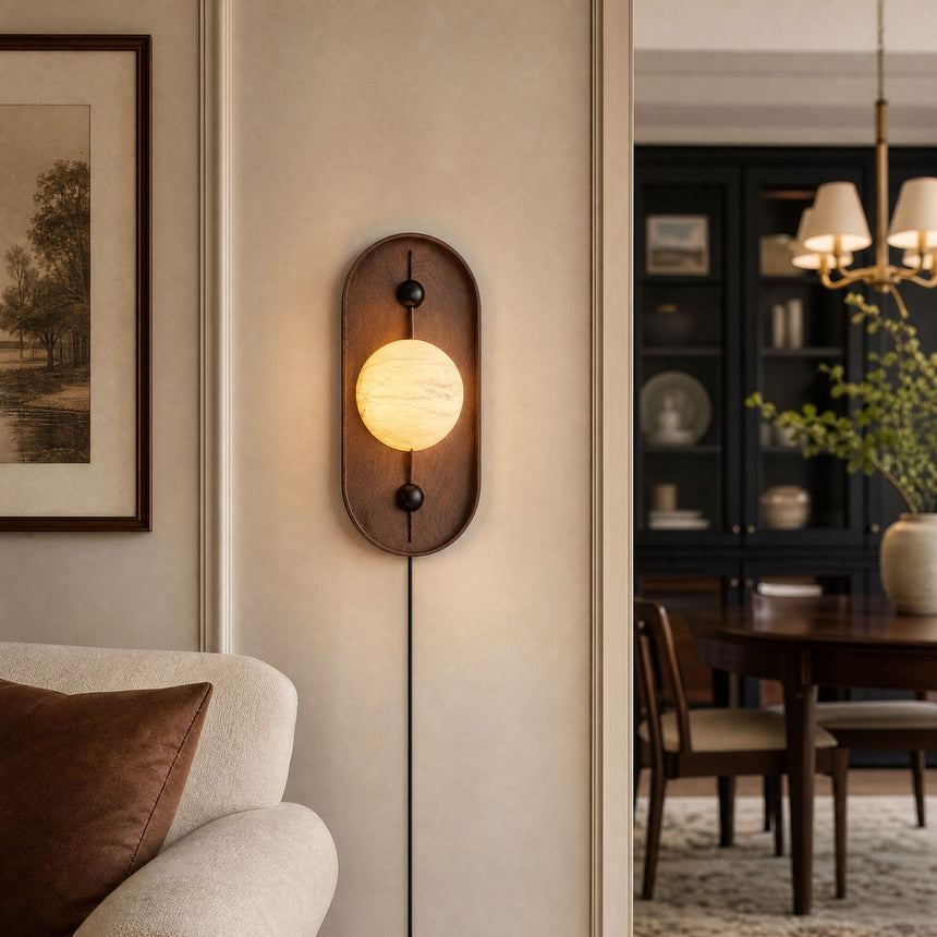Lamp lit beside a framed print with a dining table visible beyond it