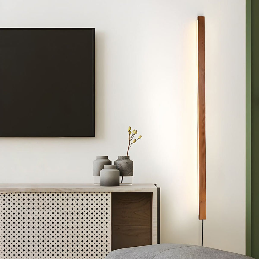 Walnut bar lit vertically beside a dark wall panel and a sideboard