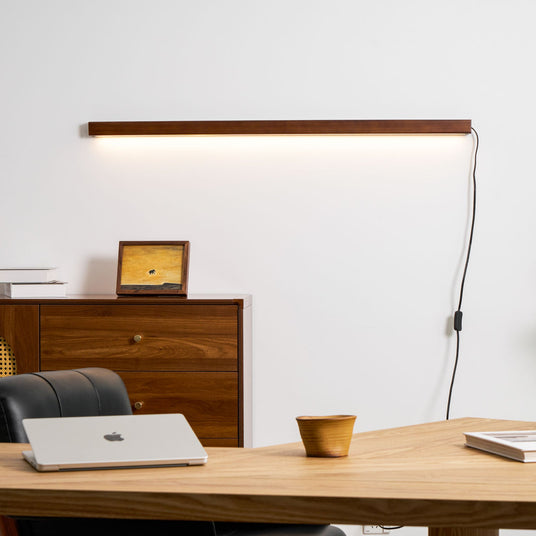 Walnut bar lit above a wood desk with a laptop and a cup