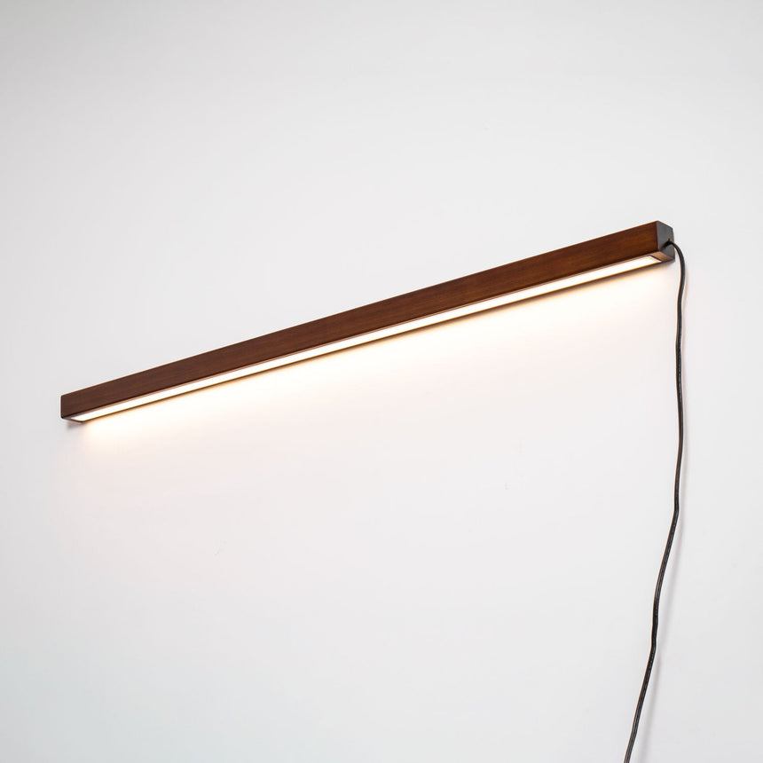 Walnut bar lit horizontally, the diffuser glowing along its length