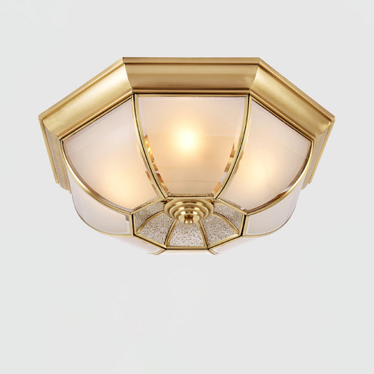 Octagonal brass ceiling light seen from below with the glass lit