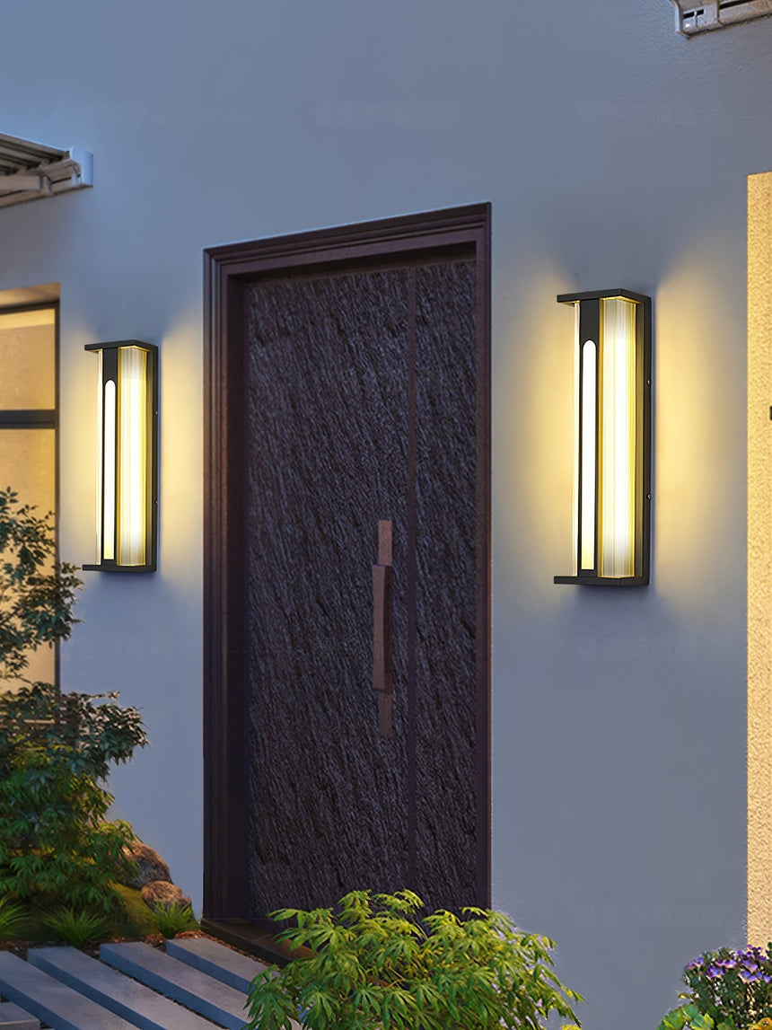 The lanterns flanking an entry door above a bed of low plants