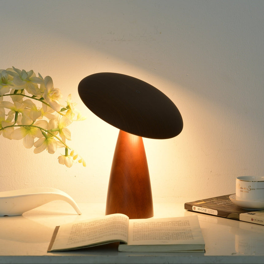 Portable table lamp lit beside white orchids and a book