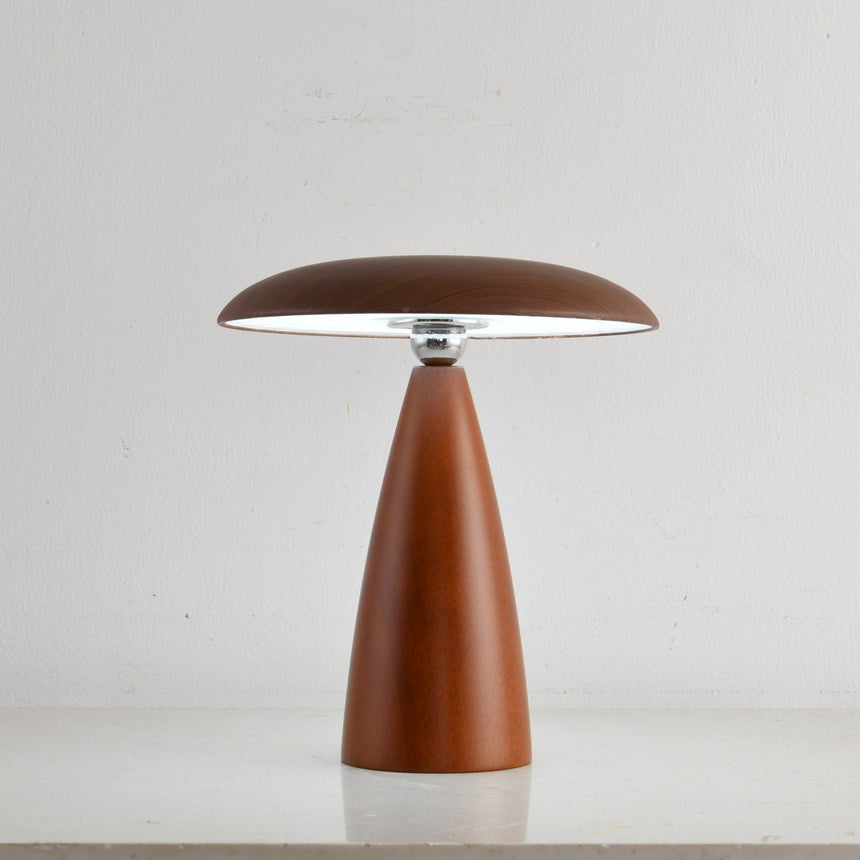 Portable table lamp on a cone base against a plain ground