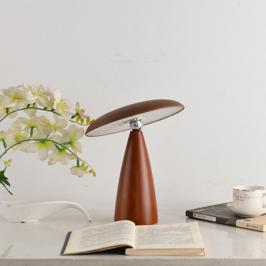 Portable table lamp lit on a desk beside an open book