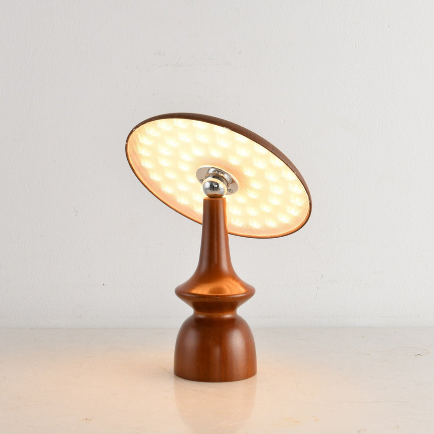 Portable table lamp on a turned spindle base, lit