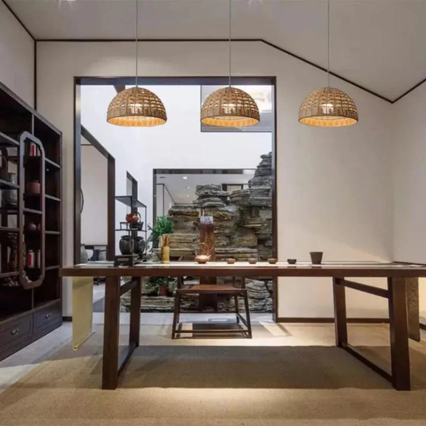 Open woven rattan dome hung in a room with pale walls