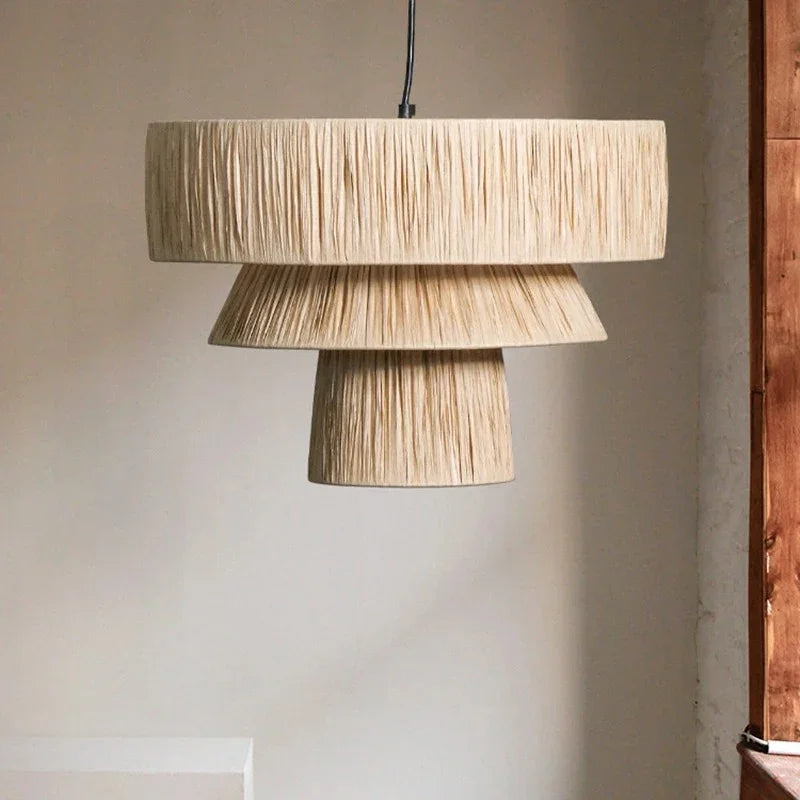 Rattan drum pendant light in two fringed tiers of natural straw, lit in a room