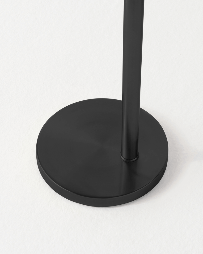 The black pole in the same round disc base, the cord leaving at the rim