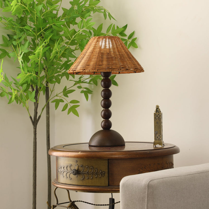 Rattan shade lamp lit in a corner on a round painted side table