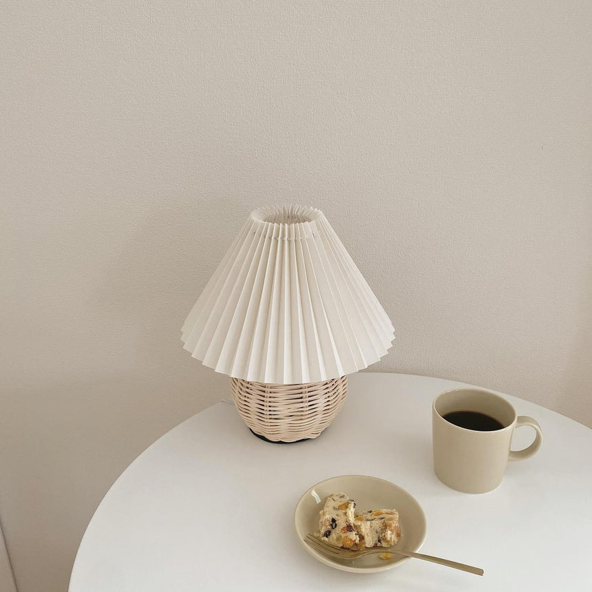 Rattan table lamp on a round white table beside a coffee cup