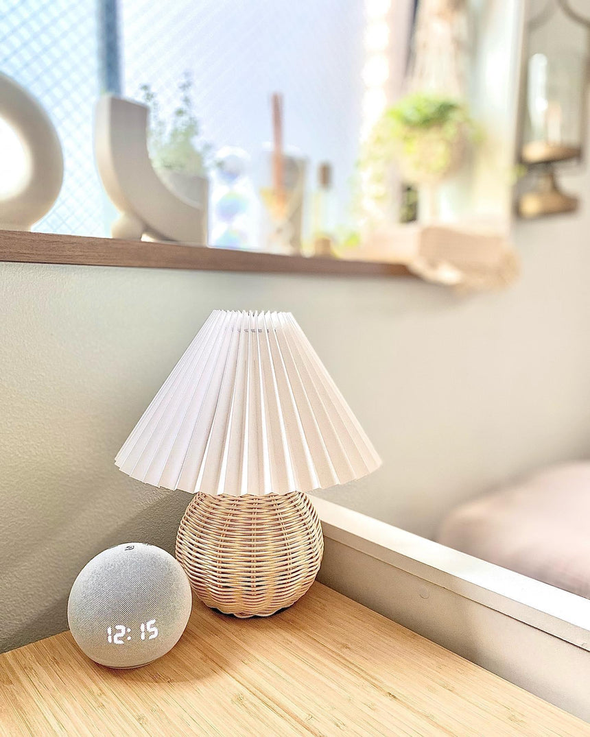 Rattan table lamp on a wooden window ledge beside a small clock