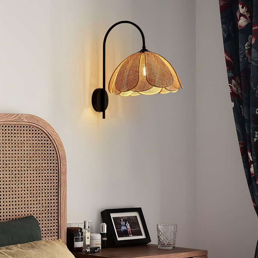 The rattan sconce above a nightstand with glasses beside a cane headboard