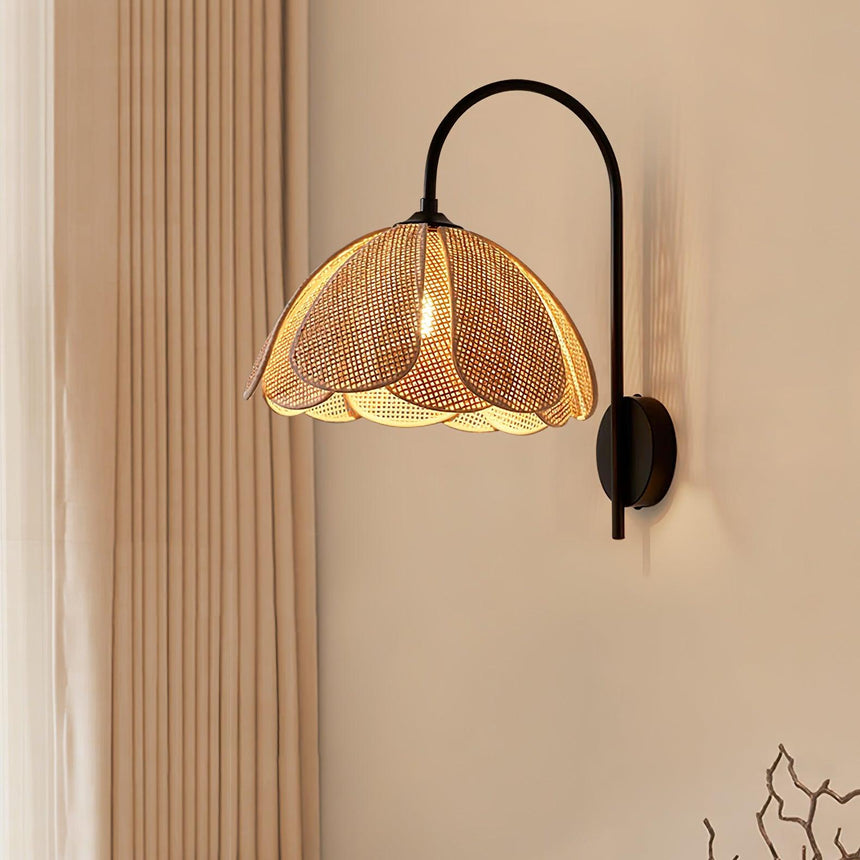 The rattan sconce lit on a beige wall beside a sheer curtain