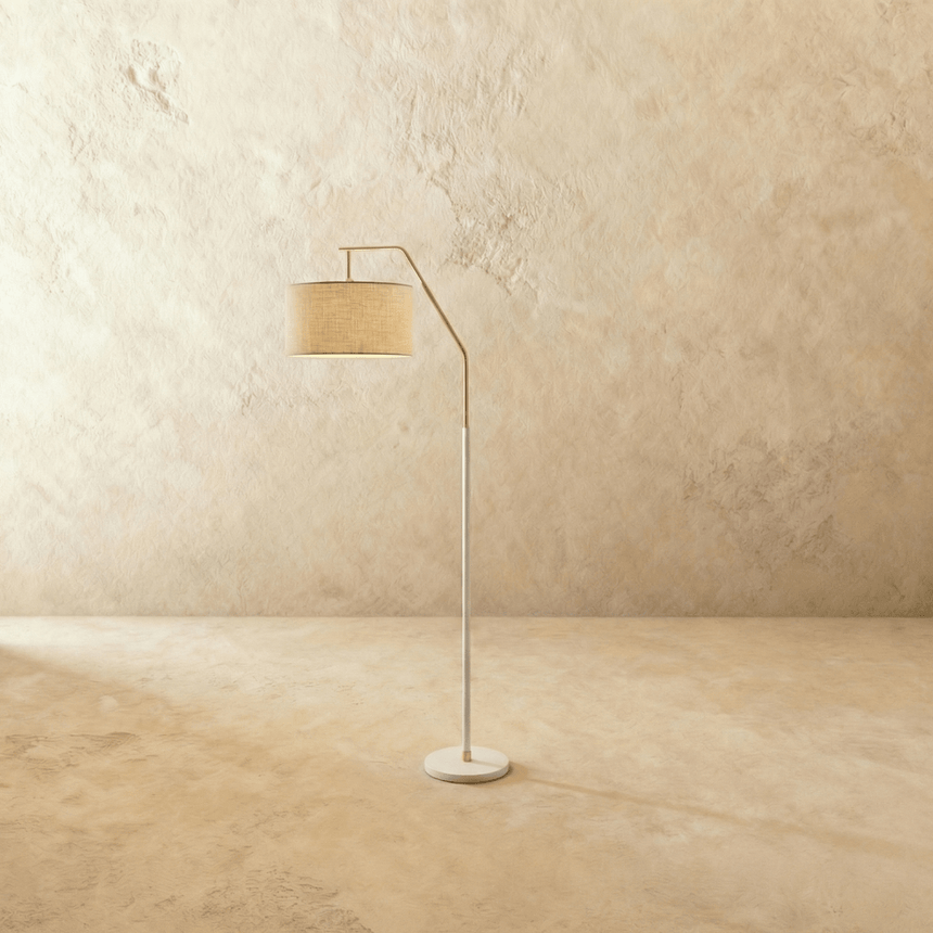 A slim white stem with a short angled arm holding a fabric drum shade above a round base