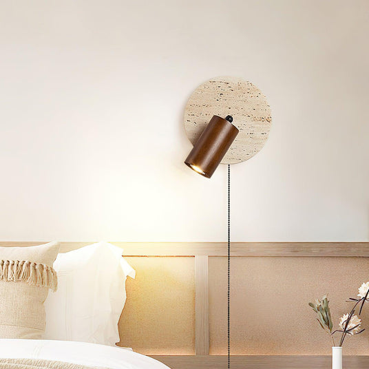 Sconce lit above a bed, the beam falling across white pillows below