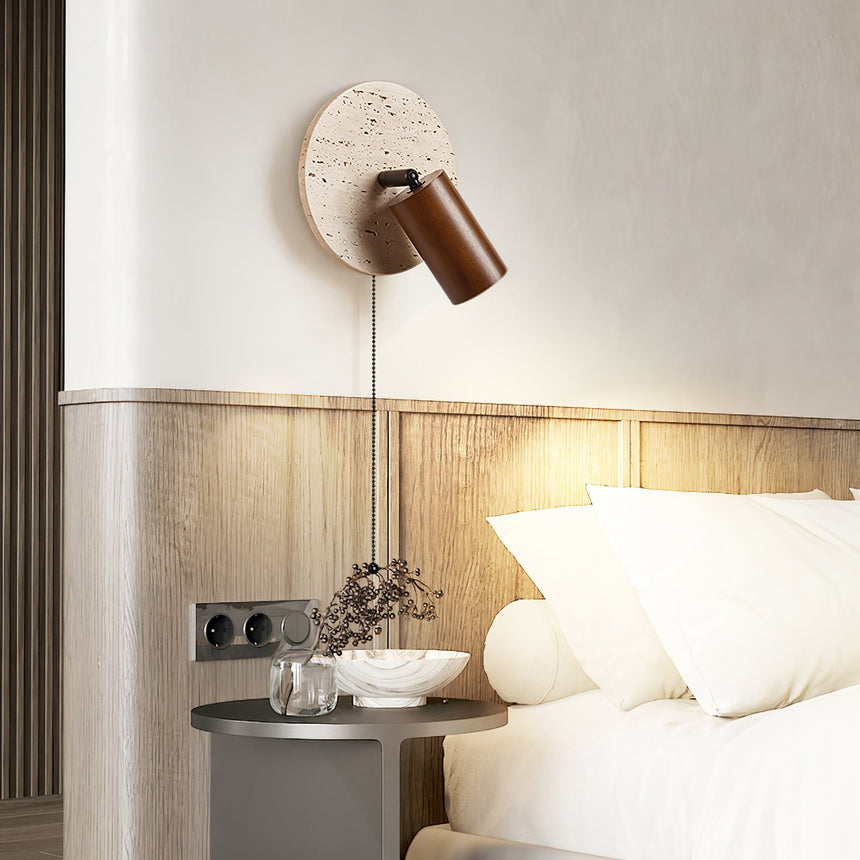 Sconce lit beside a slatted headboard above a nightstand with a small tray