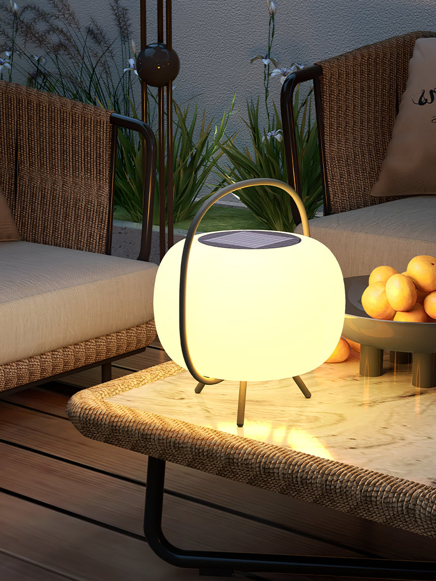 The lamp lit on a woven bench with cushions and a planter behind it