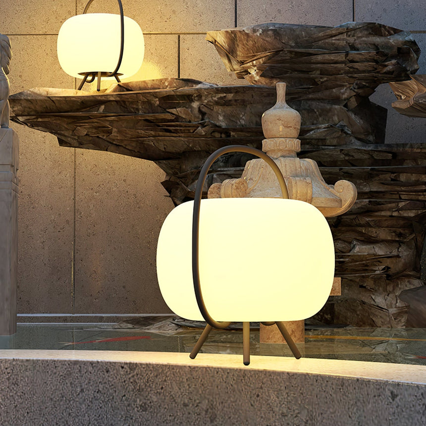 Two lamps lit beside a carved stone basin on a paved garden terrace