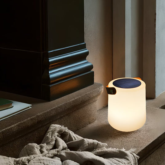 The lamp lit on a stone step beside a doorway with a linen throw on it