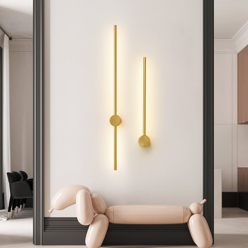 A gold pair lit above a curved bench beside a tall mirror and a dark wall