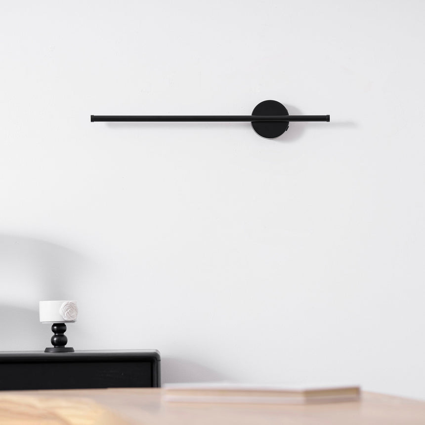 Mounted above a black nightstand with two candlesticks and a small tray