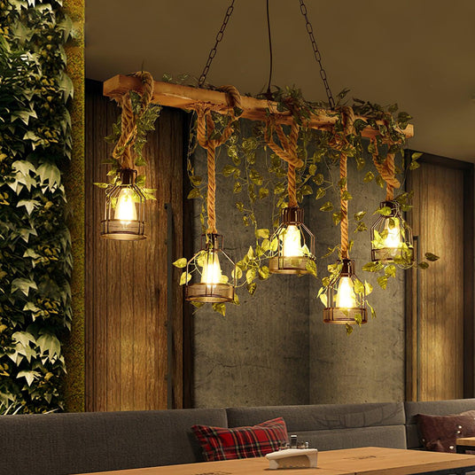 Lit above a banquette and table against a green plant wall in a dark room