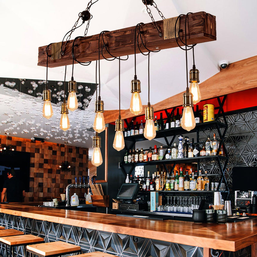 Lit along a bar counter with bottles on shelving and stools in front