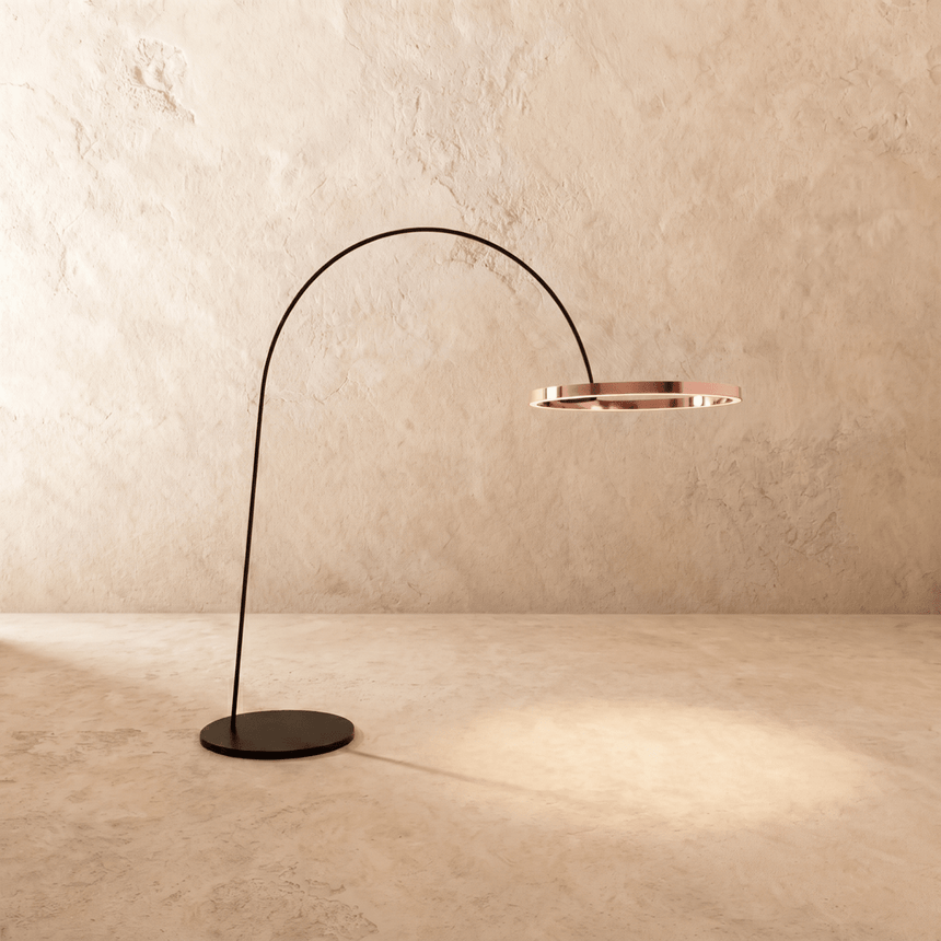 The curved black arm with a rose gold ring lit at the end above a disc base