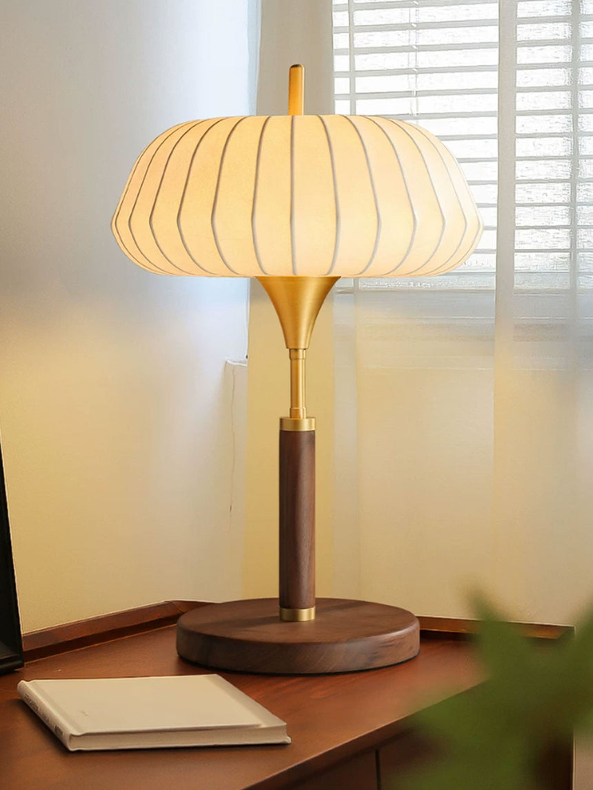 Remote control table lamp lit on a desk in front of a shuttered window